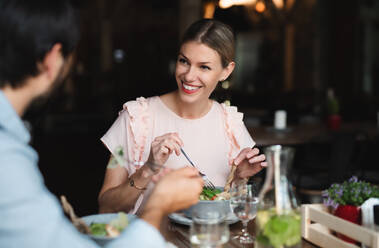 Ein glückliches Paar sitzt drinnen in einem Restaurant und isst. - HPIF15369