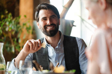 Ein glückliches Paar sitzt an einem Tisch im Freien auf einer Restaurantterrasse und unterhält sich. - HPIF15370