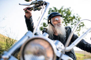 Ein älterer Mann mit Motorrad und Sonnenbrille auf dem Lande. - HPIF15384