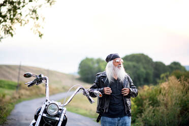 Ein älterer Mann mit Motorrad und Sonnenbrille auf dem Lande. - HPIF15406