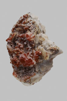 Close up detail textured red Moroccan vanadinite stone on gray background - FSIF06307