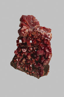 Close up detail textured red Moroccan vanadinite crystal on gray background - FSIF06316