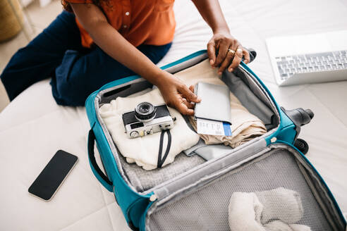 Woman packing the essentials for an exciting global trip, carefully organizing her travel documents and essentials in a suitcase. Retired woman preparing to make unforgettable memories abroad. - JLPSF30368