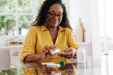 Ältere Frau, die ihre verschreibungspflichtigen Medikamente im Rahmen ihrer täglichen Routine sorgfältig einnimmt. Ältere Frau, die ihren Behandlungsplan im Rahmen der Behandlung ihrer chronischen Krankheit zu Hause einhält. - JLPSF30391