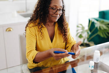 Eine ältere Frau spritzt sich Insulin, um ihren Blutzuckerspiegel zu kontrollieren. Eine Frau, die ihren Diabetes mit Hilfe eines intelligenten medizinischen Geräts in den Griff bekommt, um ihre Medikamente wie vorgeschrieben einzunehmen und ihre Gesundheit zu erhalten. - JLPSF30394