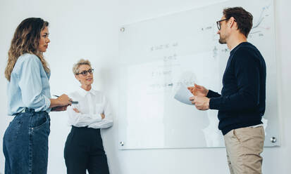 Group of three financial professional discussing numbers in a business meeting. Team of business people brainstorming solutions for a project as they work towards the success of their company. - JLPPF01871