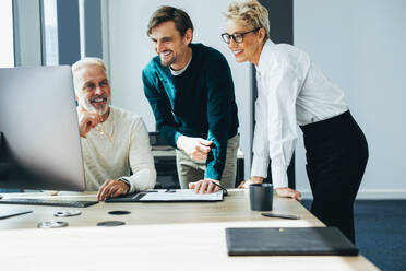 Eine Gruppe glücklicher und professioneller Geschäftsleute, sowohl männlich als auch weiblich, die zusammenarbeiten und einen Computer benutzen, um erfolgreich zu sein. Ein Startup-Team arbeitet an einem Projekt in einem modernen Büro. - JLPPF01898