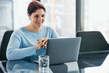 Kaukasische Geschäftsfrau, die mit einem Laptop an einer Videokonferenz mit ihren Kollegen teilnimmt. Junge weibliche Führungskraft, die während einer Online-Geschäftsdiskussion in einem Büro aufmerksam zuhört. - JLPPF01903