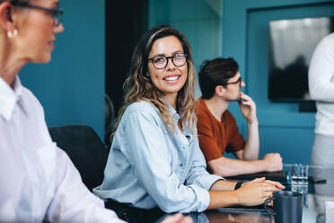 Portrait of a happy professional woman participating in a team meeting. Female business executive actively collaborating with a diverse team in a successful corporate environment. - JLPPF01916