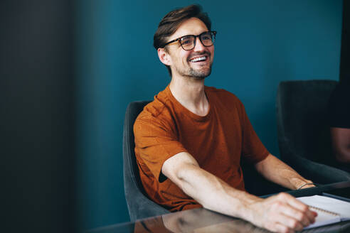 Zufriedener Geschäftsmann, der an einer gemeinsamen Sitzung bei der Arbeit teilnimmt. Erfolgreicher männlicher Unternehmer, der mit seinem Team im Sitzungssaal eines Unternehmens arbeitet. - JLPPF01919