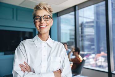 Porträt einer glücklichen und erfolgreichen Geschäftsfrau, die während einer Sitzung in einem Sitzungssaal steht. Positive weibliche Fachkraft, die in einem Team in einem Sitzungssaal zusammenarbeitet. - JLPPF01921