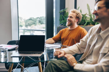 Zufriedene Geschäftsleute bei einer Besprechung mit ihrem Team, bei der aktuelle Projekte besprochen und neue Ideen entwickelt werden. Zwei Geschäftskollegen bei einer Zusammenarbeit in einem Büro. - JLPPF01932