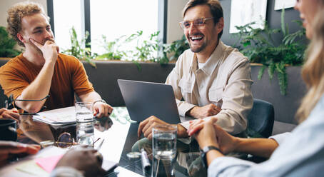 Successful business team meeting in a corporate boardroom, discussing current projects and sharing updates. Happy business people working together to achieve productive results for their company. - JLPPF01944