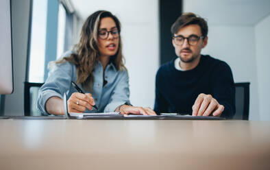 Geschäftskollegen, ein Mann und eine Frau, sitzen in einem Büro und arbeiten gemeinsam an einem Geschäftsplan. Zwei Fachleute arbeiten gemeinsam an einem erfolgreichen Weg für ihr Start-up. - JLPPF01956