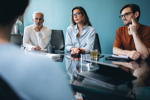 Eine Gruppe von kaukasischen Geschäftsleuten, männlich und weiblich, hört einer Diskussion in einer Teamsitzung zu. Ein Team von Geschäftskollegen arbeitet in einem Sitzungssaal an einem Projekt. - JLPPF01966