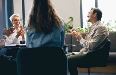 Eine Gruppe von Geschäftsleuten klatscht während einer Sitzung in die Hände, um ihren Erfolg und ihre Leistung bei einem wichtigen Projekt zu feiern. Glückliche Geschäftsleute, die als Team am Aufbau ihres Unternehmens arbeiten. - JLPPF02005