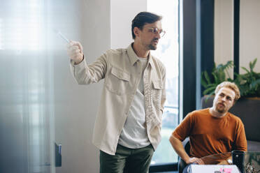 Projektleiter, der in einem Büro eine Präsentation hält und ein bevorstehendes Projekt für das Team bespricht. Geschäftsmann, der während einer Sitzung mit seinen Kollegen Kommunikations- und Führungsqualitäten zeigt. - JLPPF02010