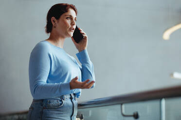 Business woman having a conversation with her clients on her smartphone in a modern corporate office. Confident female professional negotiating a business project over a phone call. - JLPPF02026