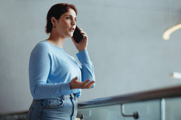 Geschäftsfrau, die sich in einem modernen Büro über ihr Smartphone mit ihren Kunden unterhält. Selbstbewusste Geschäftsfrau, die am Telefon über ein Geschäftsprojekt verhandelt. - JLPPF02026