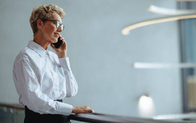 Reife kaukasische Geschäftsfrau, die mit ihren Kunden über ein Mobiltelefon kommuniziert. Erfahrene weibliche Führungskraft, die während eines Telefongesprächs mit ihren Geschäftspartnern aufmerksam zuhört. - JLPPF02031