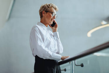 Eine erfahrene Geschäftsfrau unterhält sich am Telefon mit ihren Geschäftspartnern. Eine reife weibliche Führungskraft treibt den Erfolg ihres Unternehmens voran, indem sie in Kontakt bleibt. - JLPPF02032