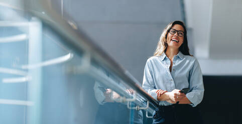 Empowered business woman smiling with confidence and self assurance as she stands in an office. Successful business woman holding a mobile phone, a tool she uses to stay productive and efficient at work. - JLPPF02040