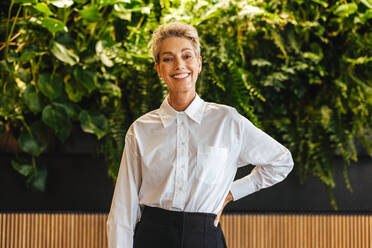 Portrait of a caucasian woman smiling with joy while standing in an eco friendly office. Professional business woman looking proud to be part of a sustainable business environment. - JLPPF02047