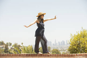 Young woman balancing on brick wall - FOLF12130