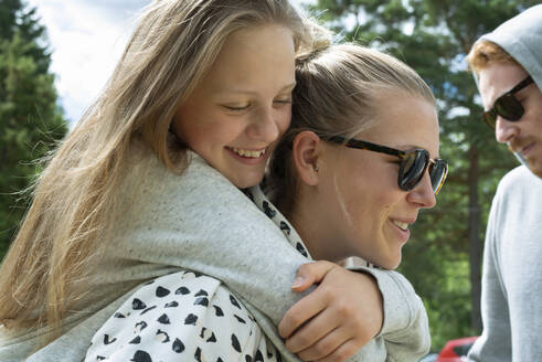 Junge Frau gibt lächelnd Schwester Huckepack Fahrt - FOLF12149