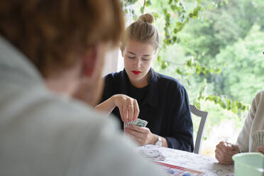 Junge Frau spielt Karten mit ihrer Familie - FOLF12151