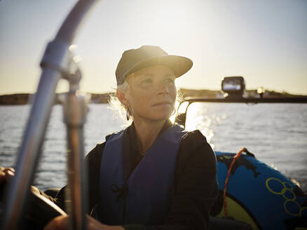 Frau fährt Boot bei Sonnenuntergang auf dem Meer - FOLF12226