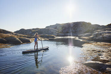 Mädchen Paddleboarding auf dem Meer unter Sonnenschein - FOLF12229