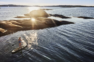 Mädchen Paddleboarding auf dem Meer bei Sonnenuntergang - FOLF12238