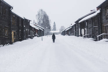 Mann geht im Schnee bei Hütten - FOLF12282