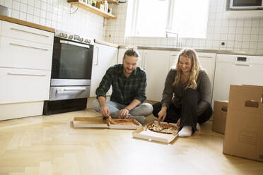 Couple eating pizza on kitchen floor - FOLF12330