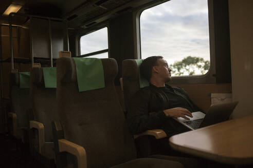 Mann mit Laptop im Zug sitzend - FOLF12336
