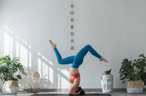 Woman doing supported headstand pose in front of wall - SNF01655