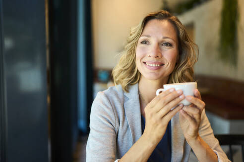 Thoughtful businesswoman day dreaming holding cup at cafe - PNEF02840