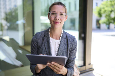 Businesswoman wearing eyeglasses holding tablet PC - PNEF02872