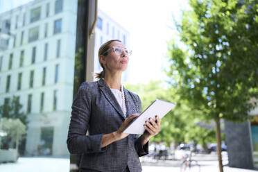 Businesswoman looking up holding tablet PC - PNEF02874