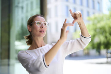 Focused businesswoman gesturing near building - PNEF02888