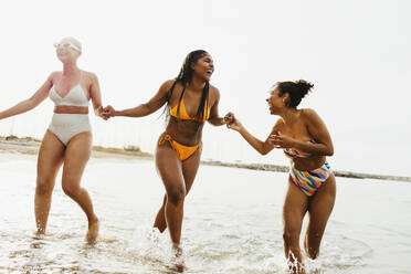 Playful friends in swimwear enjoying in sea - EBSF03352