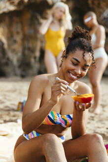 Junge Frau im Bikini genießt Mango am Strand - EBSF03360