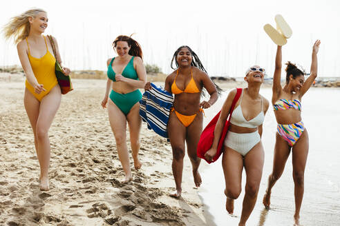 Carefree friends in swimwear running at beach - EBSF03377