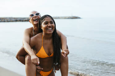 Two young women wearing bikinis sitting back to back on Ipanema beach, Rio  De Janeiro, Brazil stock photo