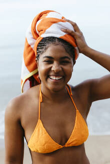 Glückliche Frau mit in Handtuch gewickelten Haaren am Strand - EBSF03408