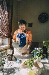 Senior woman holding flower pot preparing for planting - ADF00060