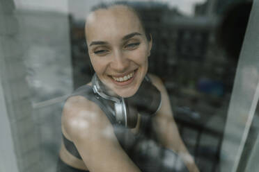 Glückliche Frau schaut aus einem Glasfenster - IEF00365
