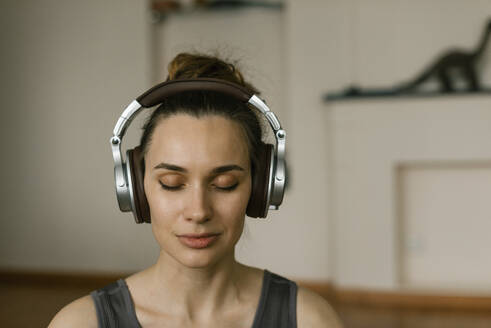 Frau hört Musik mit Kopfhörern und meditiert zu Hause - IEF00370
