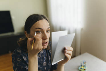 Woman applying make-up on eye at home - IEF00386